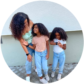 Mutter mit zwei Töchtern in Jeans-Outfits – eines der Kinder trägt eine Xplora Kinder Smartwatch für Sicherheit im Alltag.